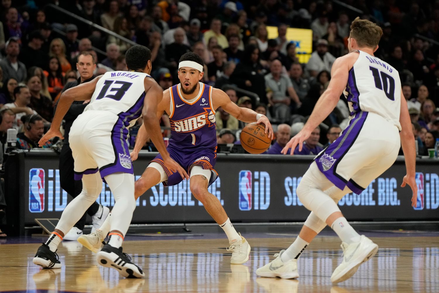 Feb 13, 2024; Phoenix, Arizona, USA; Phoenix Suns guard Devin Booker (1) drives between Sacramento Kings forward Keegan Murray (13) and forward Domantas Sabonis (10) in the first half at Footprint Center. Mandatory Credit: Rick Scuteri-USA TODAY Sports  